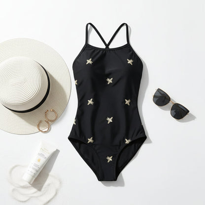 Flat lay of bee embroidered swimsuit with accessories